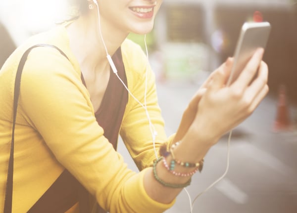 Young woman using headphones to listen to her phone. 