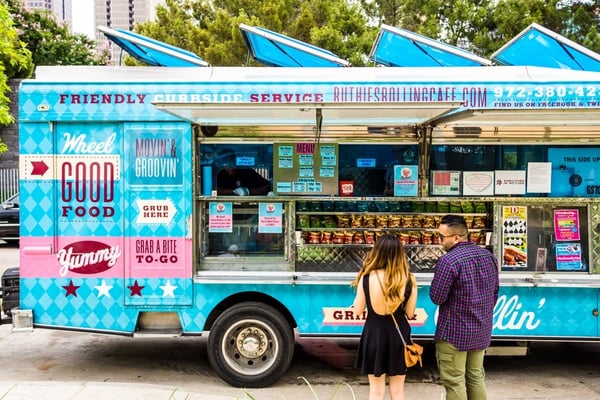 Regency April Blog9.jpg Two customers standing next to a bright blue food truck