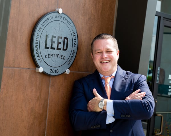 Abe Pacetti posing in front of a LEED Certified plaque.