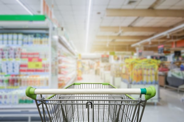 Behind a shopping cart in a grocery store. 