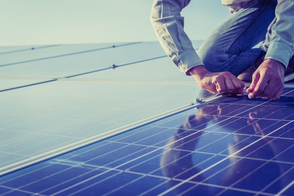 man on roof measuring solar panels