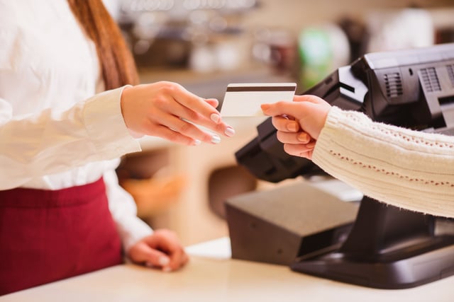 A shopper handing their credit card to an employee. 