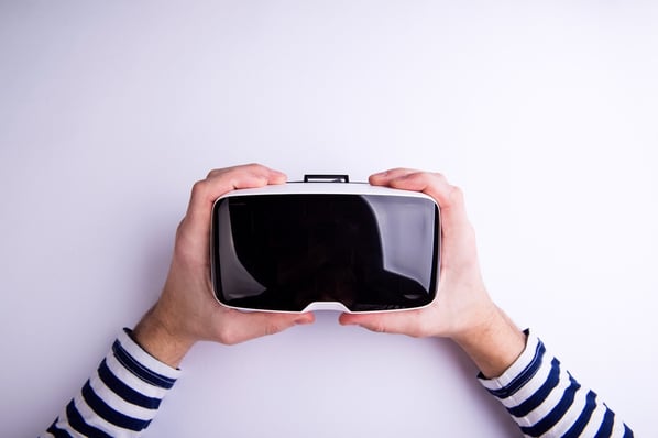 Overhead view of two hands holding a virtual reality headset. 