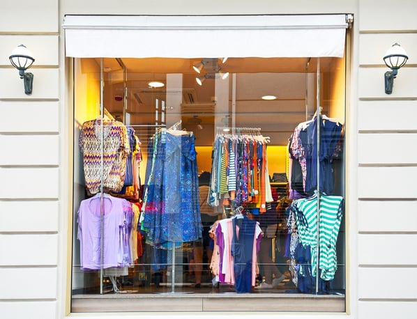 Racks of women's clothes in a store window. 