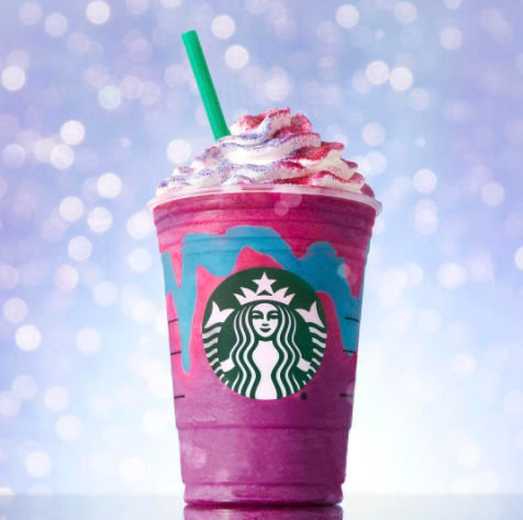 A purple Unicorn Frappucino with sprinkles and whipped cream on top.