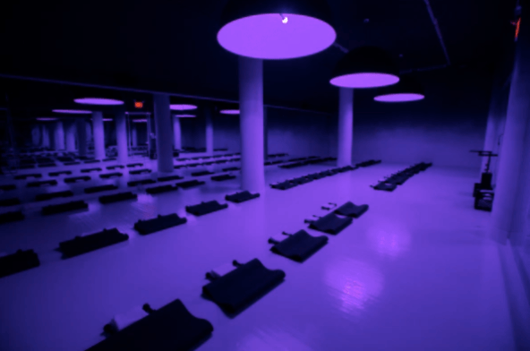 Inside a SoulCycle studio lit by purple lights. 