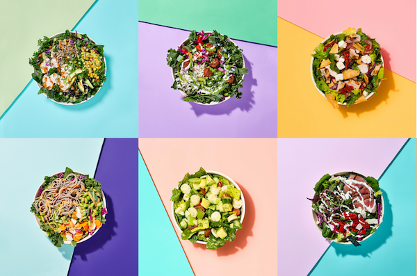 Overhead view of six bowls of various salads with a background made of color triangle shapes. 