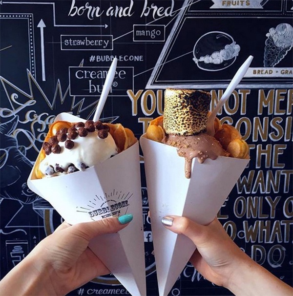 A close-up of two hands holding ice cream inside Milkcraft. 