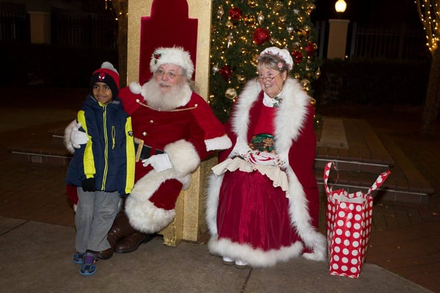 Boy telling Santa what he wants for Christmas as Mrs. Claus sits next to them