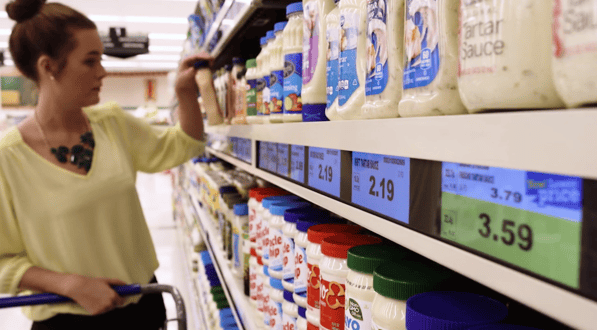 Woman looking at shelves of salad dressings. 