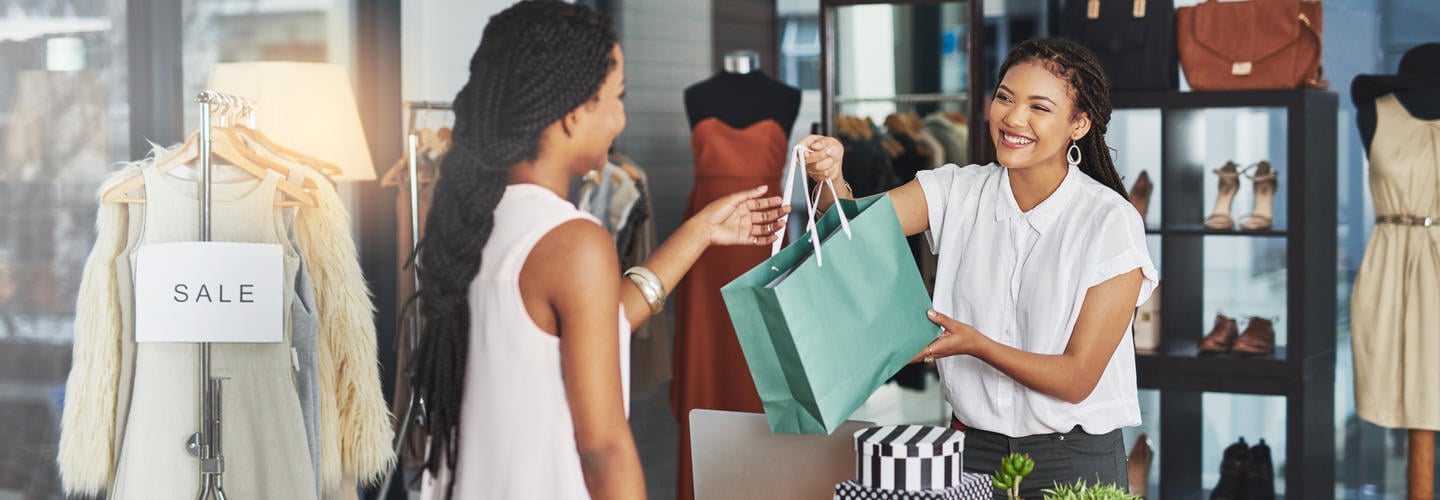 cashier handing a woman a teal shopping bag
