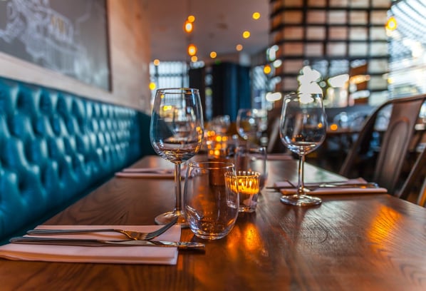 Glasses on a long wooden table in a restaurant. 