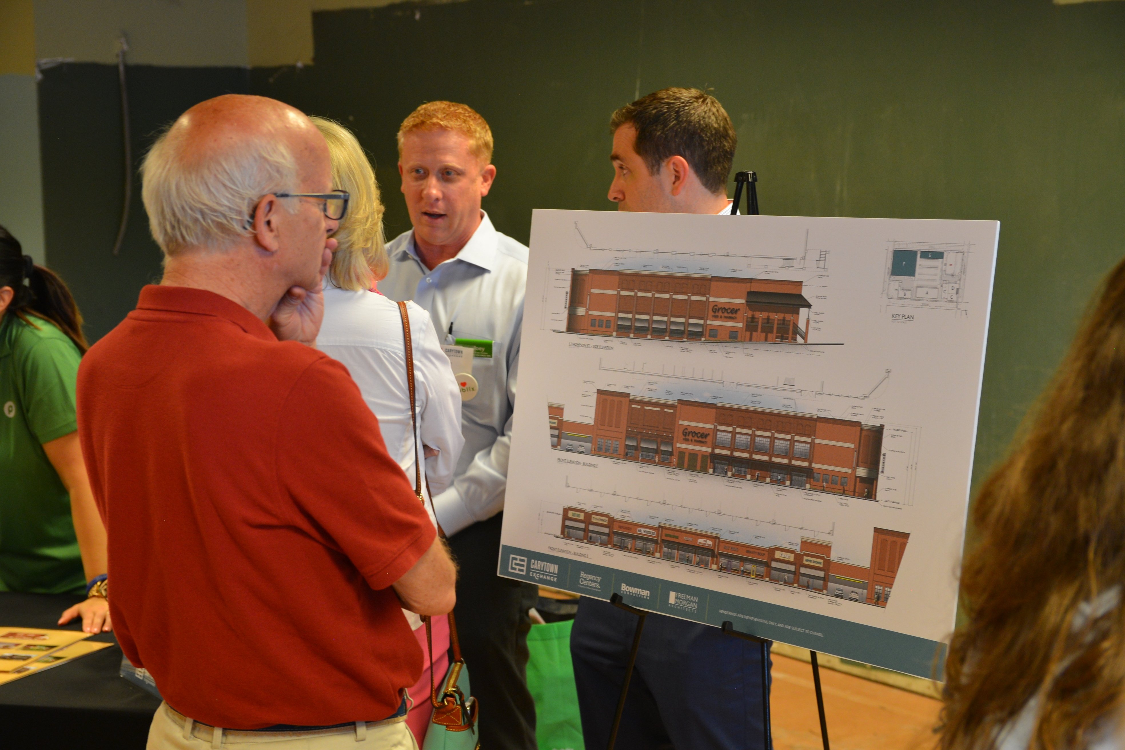 older male looking at poster of plaza renderings