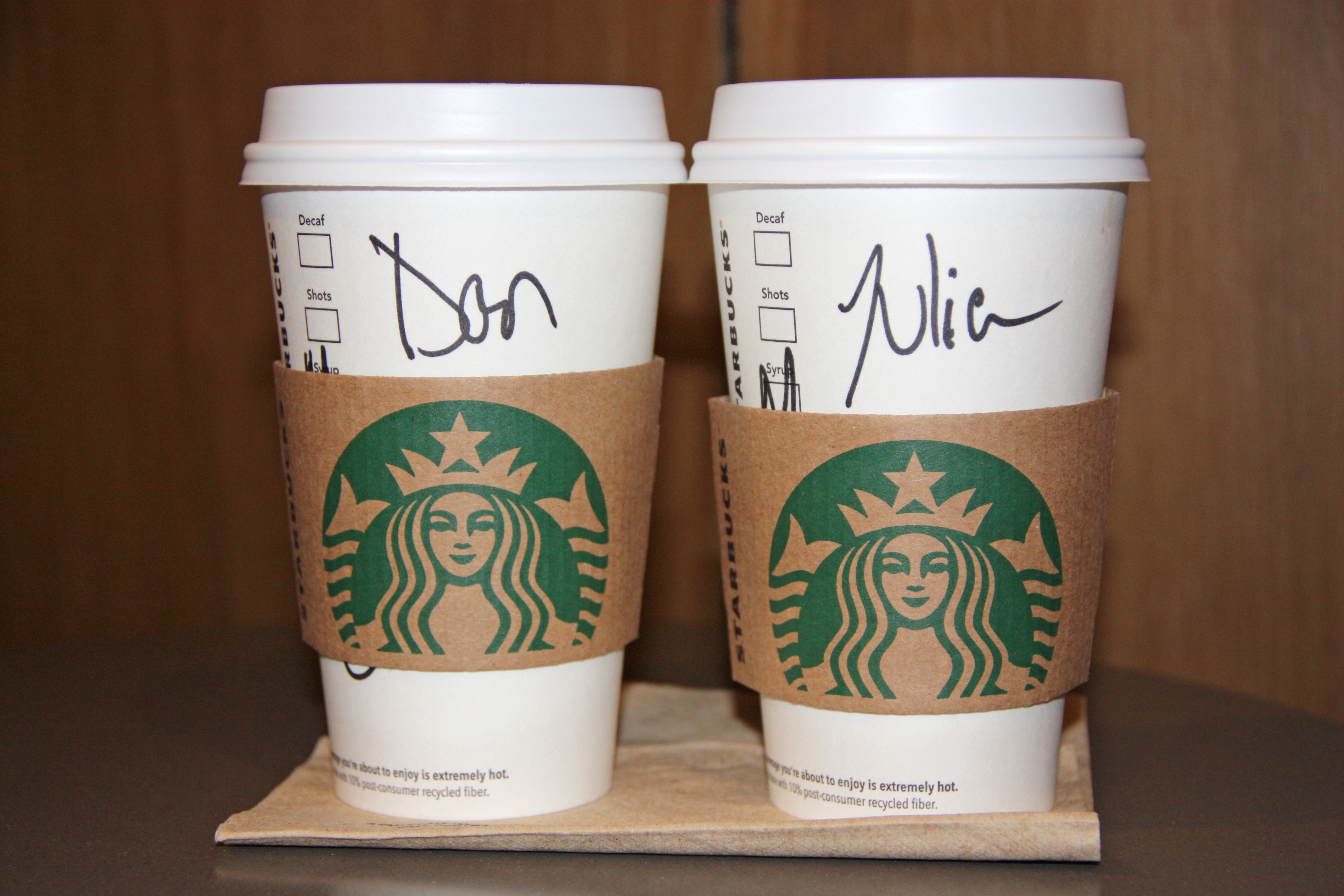 Two Starbucks cups with customers' names written on them. 