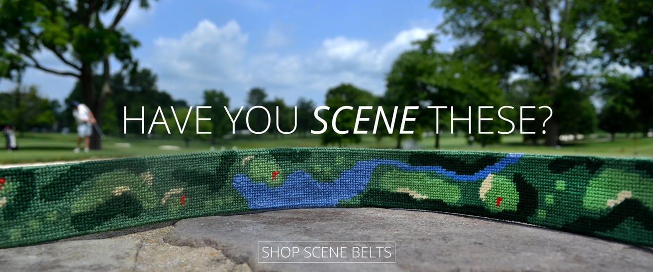 Close-up of a needlepoint belt depicting a golf course with a real golf course in the background. 